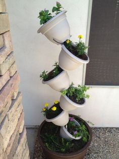 a tall white planter filled with plants next to a building