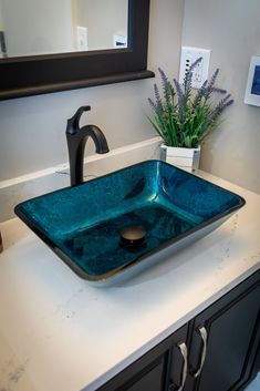 a bathroom sink with a blue glass bowl on the counter top next to a black faucet