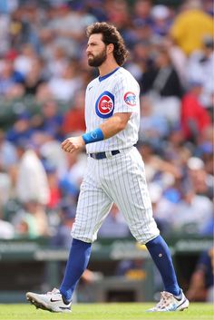 a baseball player walking on the field with his bat in hand and people watching from the bleachers