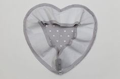 a heart shaped object hanging on the wall in front of a white background with hearts