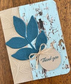 a thank you card with blue leaves and a tag on the front that says thank you