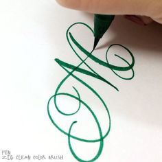 a person is writing on paper with a green pen