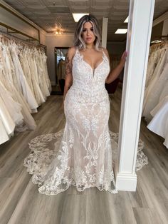 a woman standing in front of a rack of wedding dresses