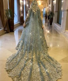 a woman in a blue wedding gown standing on the floor with her back turned to the camera