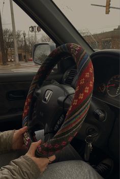 a person is driving a car with a steering wheel cover