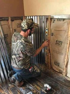 a man is working on the side of a building with metal pipes and insulation tape