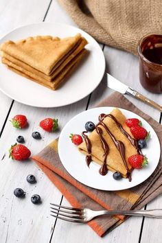 pancakes with chocolate sauce and strawberries on a plate next to a cup of coffee