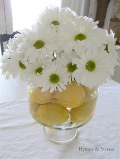 a glass vase filled with white flowers and lemons