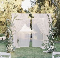 an outdoor ceremony with white drapes and flowers