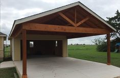 an attached carport in the middle of a yard with grass and trees behind it