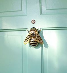 a close up of a green door with a bee on it