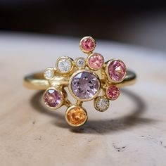 Minimalistic Dainty Cluster Ring with orange, pink and sunset colored and sapphires spinels Cluster Band wedding anniversary. Made to order Embrace the beauty of love with our exquisite 14K yellow gold cluster ring, crafted in a mesmerizing minimalistic style. Adorned with a graceful arrangement of round orange and pink sapphires at the center, it radiates a vibrant and passionate aura. Enhancing its allure are sparkling purple sapphires and dazzling diamonds gracefully placed on the sides, addi Sunset Ring, Starburst Ring, Cluster Diamond Ring, Pink Diamonds, Spinel Ring, Pink Spinel, Minimalistic Style, Purple Sapphire, Classy Jewelry