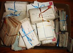 an open box filled with lots of old envelopes and papers on top of a wooden table