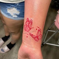 a woman's arm with two red butterflies on it