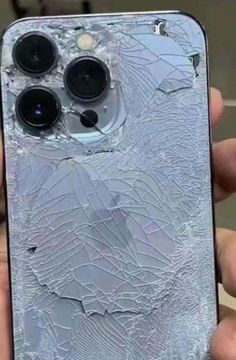 a broken cell phone in someone's hand with the screen cracked off and there is no image on it