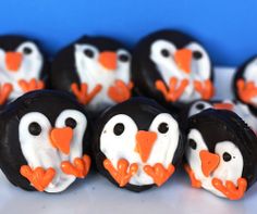 chocolate penguins decorated with white and orange icing on top of a table next to each other