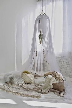 a bed with white sheets and pillows in a room next to a curtained window