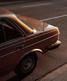 an old brown car parked on the side of the road next to a parking meter