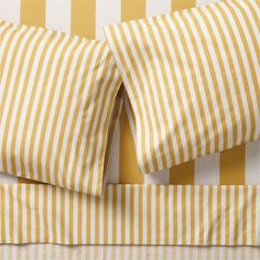 yellow and white striped bedding with matching pillowcases on top of each other