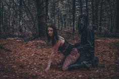 a woman dressed as a demon crouches in the woods next to a creepy creature