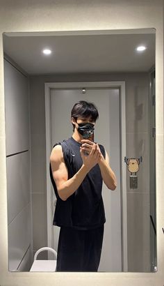 a man taking a selfie in front of a bathroom mirror with his cell phone