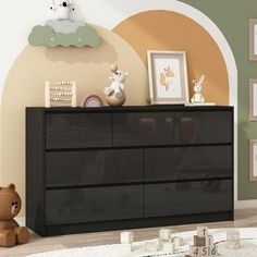 there is a black dresser in the room with pictures on it and a teddy bear