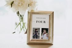 a gold frame with four photos in it next to a vase filled with white flowers