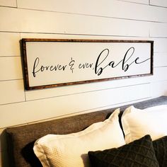 a bed with pillows and a sign on the wall above it that says forever & ever babe