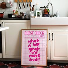 a pink sign sitting on top of a kitchen floor next to a white sink and counter