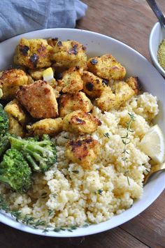 a bowl filled with rice, broccoli and tofu next to a spoon