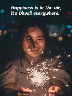 a woman holding a sparkler in her hands with the caption happiness is in the air, it's diwali everywhere