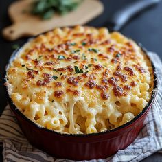 a casserole dish filled with macaroni and cheese on top of a striped cloth