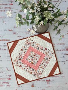 a potted plant sitting on top of a table next to a piece of quilt