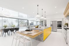 a modern kitchen with yellow accents and marble counter tops, along with an island in the middle