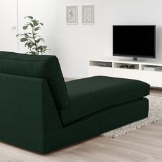 a living room with a large green couch and television on top of the entertainment center