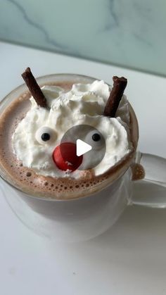 a close up of a cup of hot chocolate with whipped cream and a reindeer nose