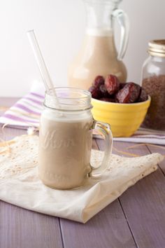 a smoothie in a mason jar with a straw on the side and cherries next to it