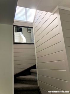 stairs leading up to the upper level of a house with white walls and shutters