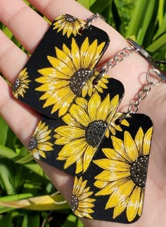 two yellow sunflowers are on black tags in the palm of someone's hand