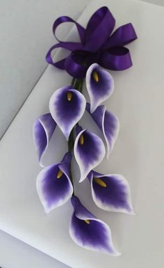 purple flowers are arranged on top of a white box with a purple ribbon around it