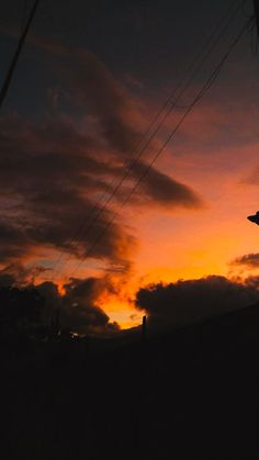 the sun is setting behind some power lines