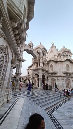 people are sitting on the steps in front of an ornate building with arches and doorways