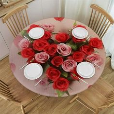 the table is set with white plates and red roses