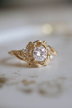 a close up of a ring with a diamond in it on a white table top