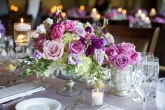 a centerpiece with purple and white flowers on a table