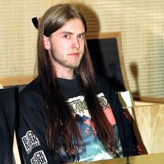 a man with long hair sitting in a chair