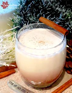 a glass filled with liquid next to cinnamon sticks