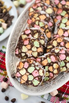 there are many pieces of chocolate candy on the plate and in the background is cookies