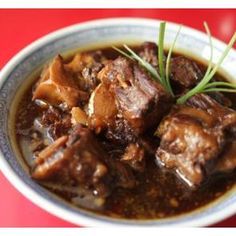 a close up of a bowl of food with meat and gravy on it