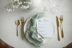 a white plate topped with a menu next to gold utensils and silverware